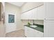 Bright laundry room with white cabinets and green countertop at 2357 Emerald Lake Dr, Sun City Center, FL 33573