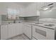 White cabinets, gray backsplash, and white appliances in this galley style kitchen at 2401/2403 23Rd W Ave, Bradenton, FL 34205