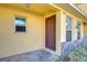 Front entrance of a yellow townhome with a brown door at 37650 Aaralyn Rd, Zephyrhills, FL 33542