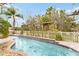 Inviting freeform pool with a wooden pergola and tile accents at 10829 Breaking Rocks Dr, Tampa, FL 33647