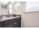 Bathroom with dark vanity, granite countertop, and a mirror at 30868 Kelmin Ter, Wesley Chapel, FL 33543