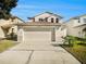 Two-story house with beige exterior, attached garage, and landscaping at 32328 Fish Hook Loop, Wesley Chapel, FL 33545