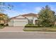 One-story house with a red door, two-car garage, and manicured landscaping at 11910 Climbing Fern Ave, Riverview, FL 33579