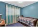 Small bedroom with twin bed, blue walls, and window curtains at 5711 S Coolidge Ave, Tampa, FL 33616