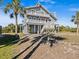 Two-story house exterior with elevated deck and surrounding palm trees at 1614 Sea Breeze Dr, Tarpon Springs, FL 34689