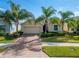 Tan one-story house with palm trees and brick driveway at 1861 Pacific Dunes Dr, Sun City Center, FL 33573