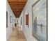 Long hallway with hardwood floors, exposed beams, artwork, and windows at 1571 Oceanview Dr, St Petersburg, FL 33715