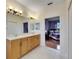 Bathroom with double vanity, wood cabinets, and view of bedroom at 2003 Captiva Ct, Sun City Center, FL 33573