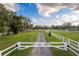 Gated entrance to a community with grassy fields and white fencing at 2972 Lake Saxon Dr, Land O Lakes, FL 34639