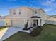 Two-story house with beige exterior, two-car garage, and landscaped front yard at 38296 Sonnet Landing Ave, Zephyrhills, FL 33540