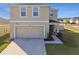 Two-story house with beige exterior, two-car garage, and front yard landscaping at 38296 Sonnet Landing Ave, Zephyrhills, FL 33540