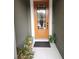 Orange front door with glass panels and landscaping at 5508 Viola Lee Way, Lutz, FL 33558