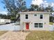 Two-story house with orange door, paver driveway, and white fence at 6701 E 19Th Ave, Tampa, FL 33619