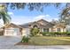 Beautifully landscaped home with a three-car garage and well-manicured lawn on a sunny day at 8701 Ballantrae Way, Tampa, FL 33647