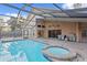 Backyard with a screened-in pool, spa, grill, and patio area at 8701 Ballantrae Way, Tampa, FL 33647