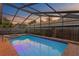 Beautiful pool reflecting the sunset in an enclosed screen with a hot tub and brick surroundings at 8701 Ballantrae Way, Tampa, FL 33647