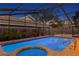 Screened in pool with a hot tub and a brick paved deck during the evening at 8701 Ballantrae Way, Tampa, FL 33647