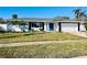 Newly renovated home with white brick exterior, gray roof, and a blue front door at 3946 Doral Dr, Tampa, FL 33634