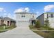 Two-story house with gray siding, two-car garage, and landscaping at 5721 Hollingworth Trl, Wesley Chapel, FL 33545