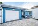 Front view of a charming blue house with a white garage door and a spacious front yard at 17744 1St E St, Redington Shores, FL 33708