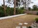 Backyard with patchy grass, trees, and a low wall at 237 Orduna Dr, North Port, FL 34287