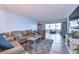 Open living room with a taupe sofa, large TV and view into the dining area at 5555 Gulf Blvd # 209, St Pete Beach, FL 33706