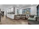 Open concept living space with hardwood floors, a sectional sofa, and white kitchen cabinets at 7209 N Highland Ave, Tampa, FL 33604