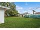 Large backyard with green grass, mature trees, and a privacy fence at 51 Lexington Dr, Dunedin, FL 34698