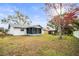 Back exterior view of house with a screened porch and a spacious grassy yard at 6543 Barcelona Blvd, Brooksville, FL 34602