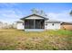 Back exterior view of house with a screened porch and a spacious grassy yard at 6543 Barcelona Blvd, Brooksville, FL 34602