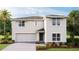 Two-story house with light-beige exterior, dark-gray door, and landscaping at 3040 Living Coral St, Wimauma, FL 33598