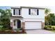 Two-story house with a two-car garage, stone accents, and landscaping at 33182 Osprey Peak Way, San Antonio, FL 33576