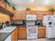 Kitchen with wood cabinets, white appliances, and dark green countertops at 1241 Redondo Way, Wesley Chapel, FL 33543