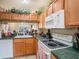 Kitchen features wood cabinets, white appliances, and a view to living area at 1241 Redondo Way, Wesley Chapel, FL 33543