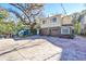 Tan two-story house with a brown double garage door and mature trees in front at 1745 E Mulberry Dr, Tampa, FL 33604