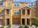 Front view of tan townhome with landscaping and two-car garage at 8958 White Sage Loop, Lakewood Ranch, FL 34202
