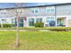 Back view of townhouses showcasing a grassy yard and screened patio at 2441 Foggy Creek Cir, Clearwater, FL 33764