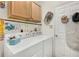 Bright laundry room with washer, dryer, cabinets, and rod for hanging clothes at 5215 New Brittany Ln, Zephyrhills, FL 33541