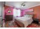 Spacious bedroom with pink and orange walls, a queen bed, and an en-suite bathroom at 5901 N Cherokee Ave, Tampa, FL 33604