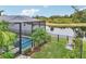 Private backyard with a screened pool area, lush tropical landscaping, and peaceful lake views at 6028 Milestone Dr, Apollo Beach, FL 33572