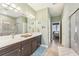Bathroom with double sink vanity, shower with glass door and neutral tile floors at 6028 Milestone Dr, Apollo Beach, FL 33572