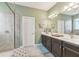 Bathroom with double sink vanity, shower with glass door, and neutral tile floor at 6028 Milestone Dr, Apollo Beach, FL 33572