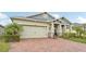 Charming home featuring a two-car garage, brick driveway, and beautifully landscaped front yard at 6028 Milestone Dr, Apollo Beach, FL 33572