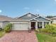 Charming home features a two-car garage, brick driveway, and beautifully landscaped front yard at 6028 Milestone Dr, Apollo Beach, FL 33572