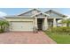 Charming home featuring a brick driveway, two-car garage, and decorative front porch at 6028 Milestone Dr, Apollo Beach, FL 33572