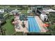 Aerial view of a community pool featuring a large, modern building, palms, lounge chairs, and orange umbrellas at 6028 Milestone Dr, Apollo Beach, FL 33572
