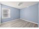 Light and airy bedroom with light blue walls, wood-look flooring, and window with blinds at 31445 Amberlea Rd, Dade City, FL 33523