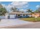 Charming ranch home with a light blue exterior, a white garage door and landscaped lawn at 3282 Honeysuckle Rd, Largo, FL 33770