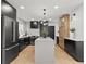 A modern kitchen featuring a spacious island, stainless steel appliances, light hardwood floors, and custom black cabinetry at 407 41St Ave, St Pete Beach, FL 33706