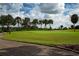 Golf course with palm trees and a paved walkway at 1205 Chevy Chase Dr, Sun City Center, FL 33573